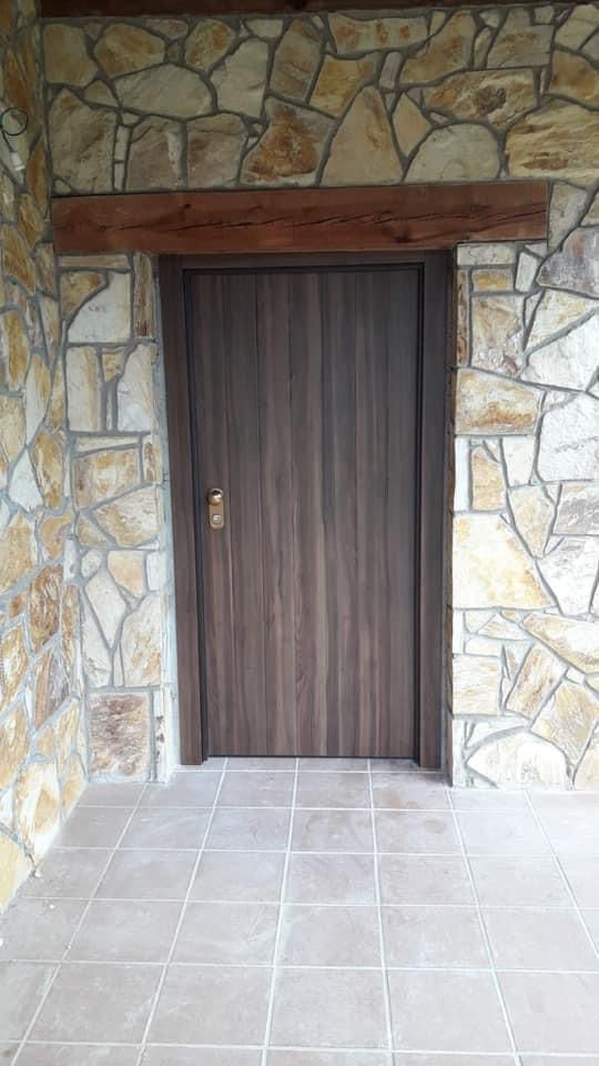 Una puerta de madera está rodeada por un muro de piedra.