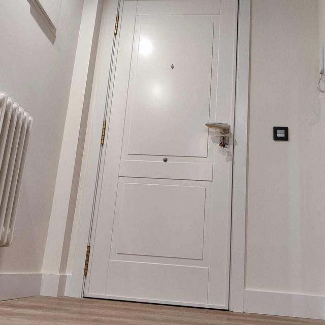 Una puerta blanca está en un pasillo al lado de un radiador.