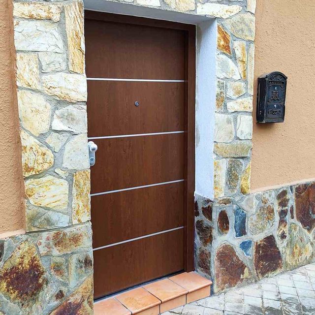 Un muro de piedra con una puerta de madera y un buzón.