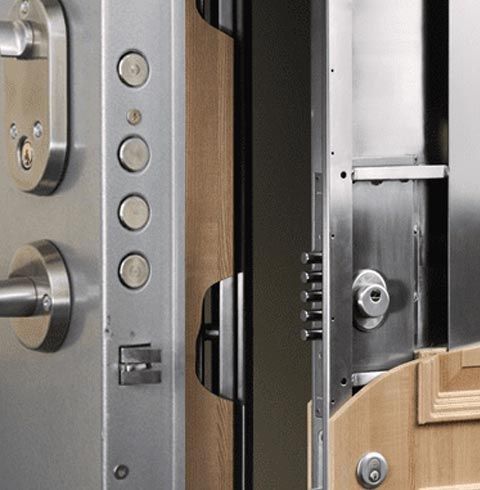 Un primer plano de una puerta de acero inoxidable con una puerta de madera al fondo.