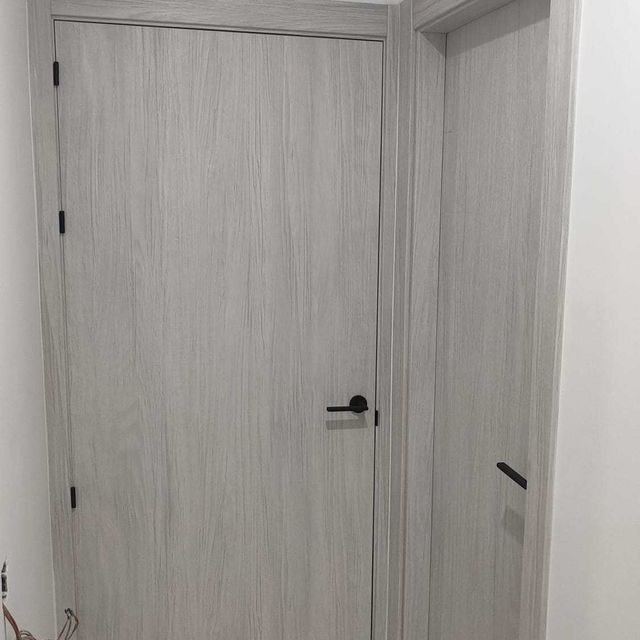 En un pasillo hay una puerta blanca con manija negra.