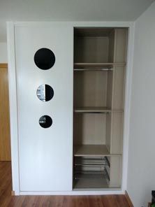 Un armario blanco con tres espejos en las puertas y estantes.
