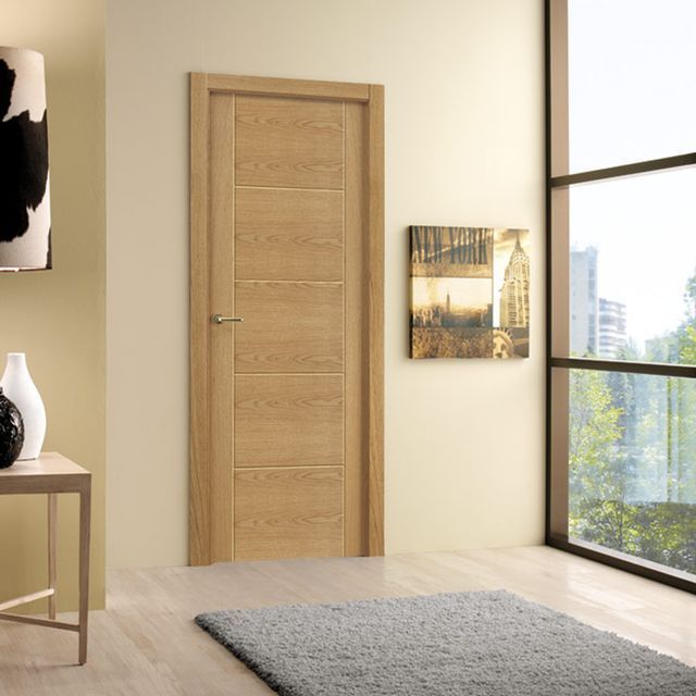 Una habitación con una puerta de madera y una ventana grande.