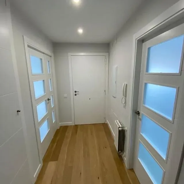 Un pasillo con puertas blancas y suelos de madera.