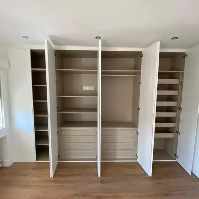 Un gran armario blanco con muchos estantes y cajones en una habitación.