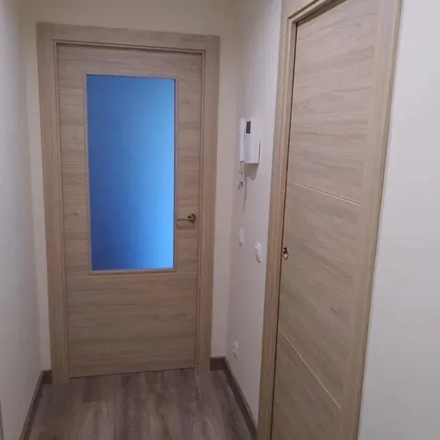 Un pasillo con una puerta de madera y una puerta de cristal.