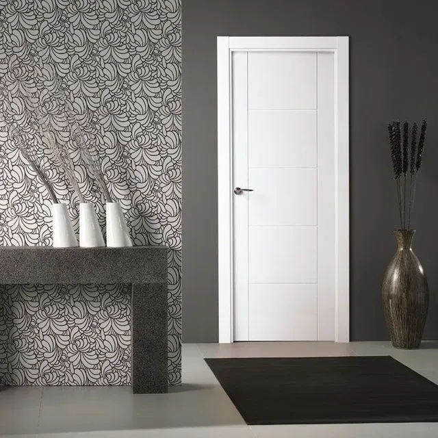 Una habitación con una puerta blanca y jarrones sobre una mesa.