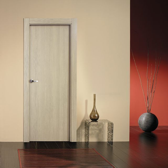 Una habitación con una puerta blanca y un jarrón sobre una mesa.