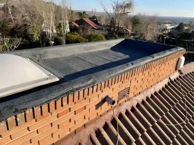 Un techo con una pared de ladrillos y un tragaluz sobre él.