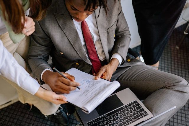 Un hombre con traje y corbata está sentado en una mesa con una computadora portátil y un cuaderno.