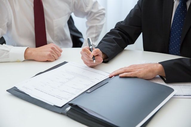 Dos hombres están sentados en una mesa firmando un documento.