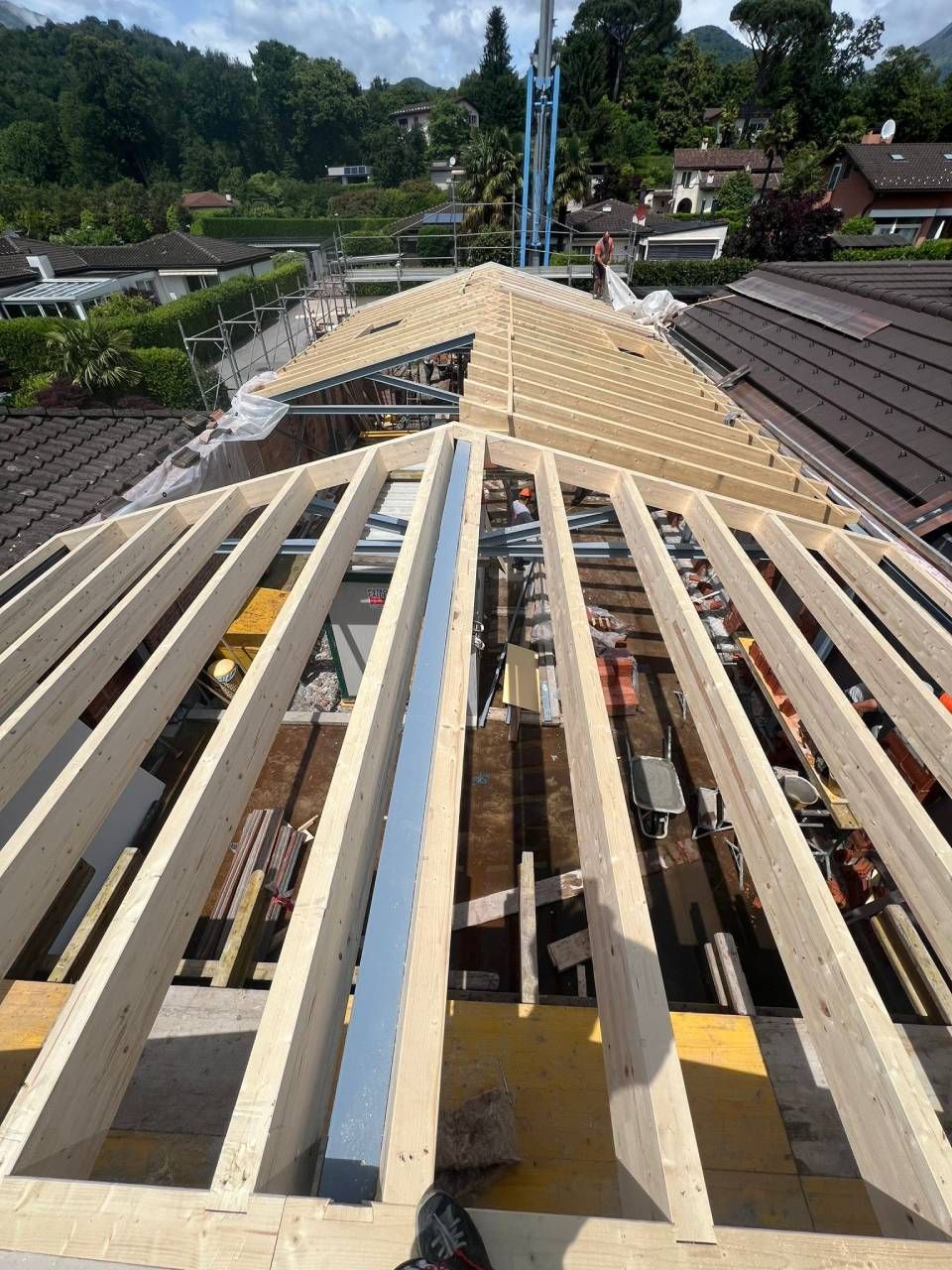 Costruzione di un tetto con travi in ​​legno a vista. Operai edili, attrezzi e uno sfondo di montagne e case.