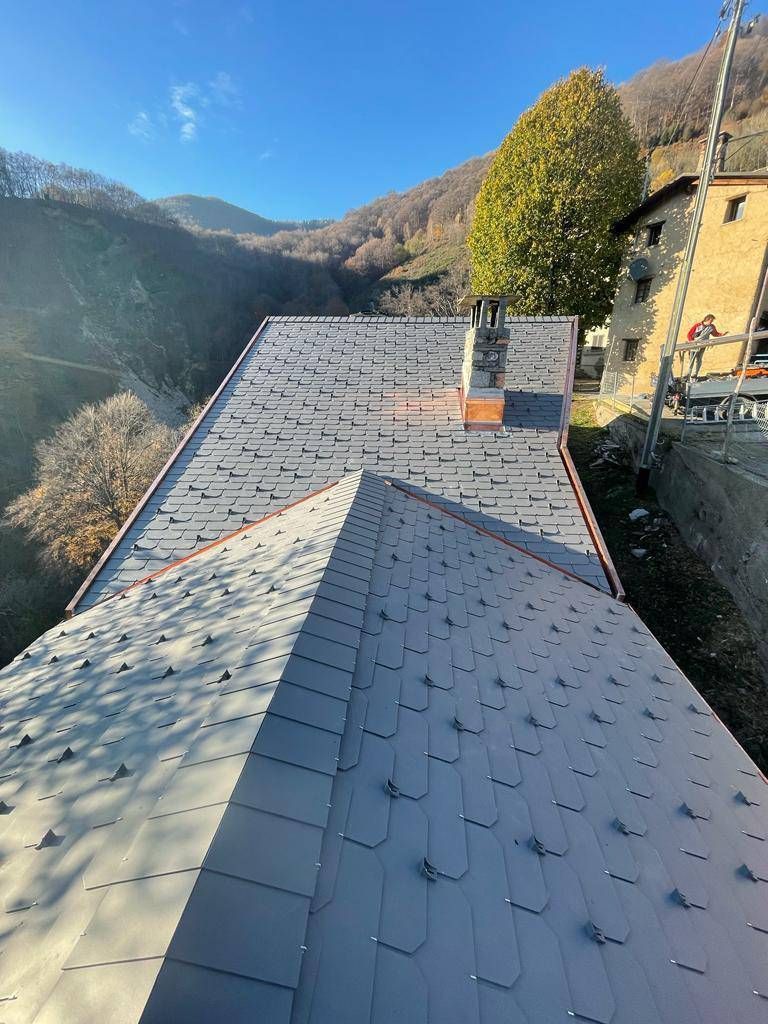 Tetto in ardesia con rivestimento in rame, incastonato in un paesaggio montuoso.