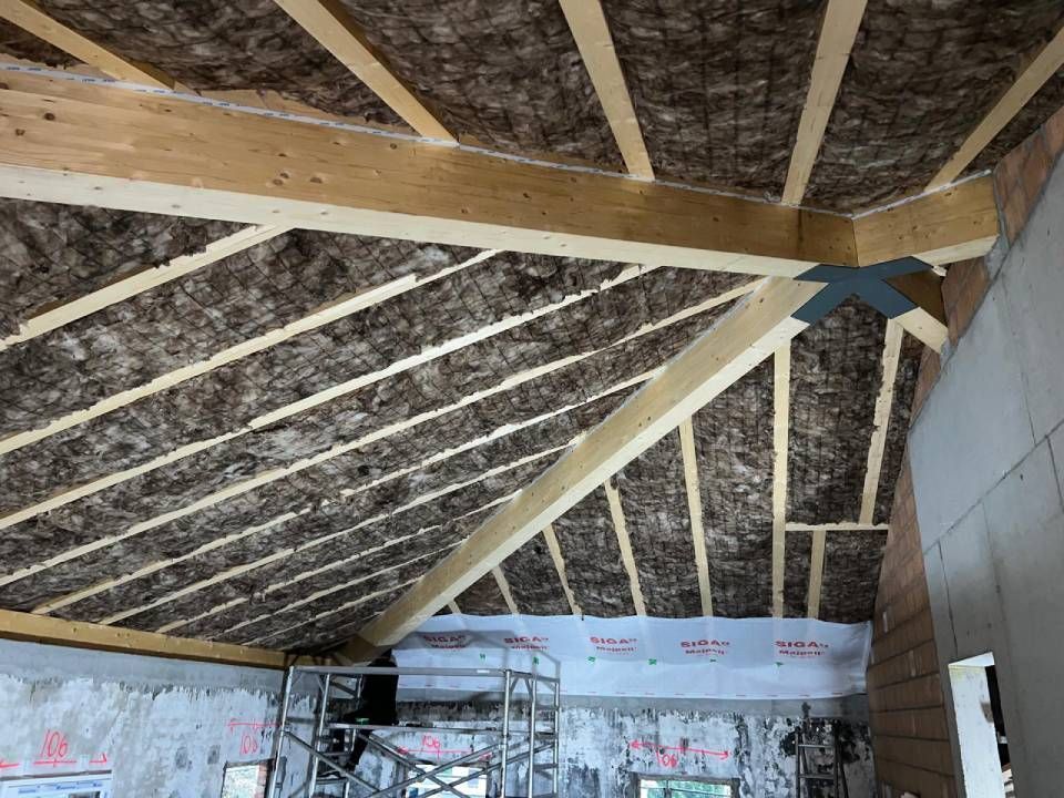 Interno di una stanza in costruzione, con travi in ​​legno e isolamento intermedio.