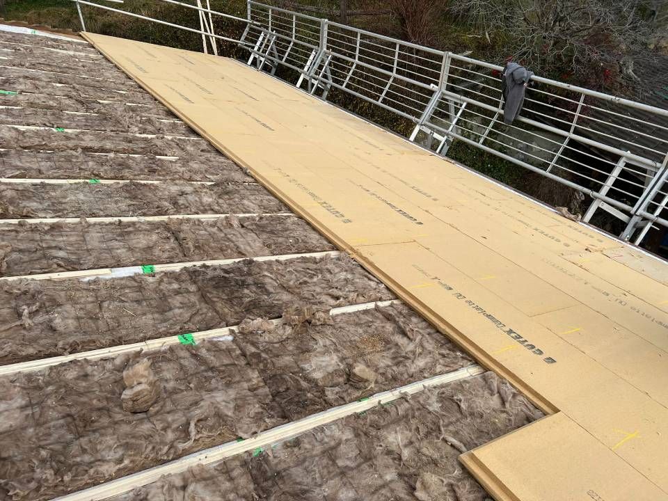 Installazione dell'isolamento del tetto. Isolamento marrone tra le travi di legno, ricoperto con assi color cuoio.