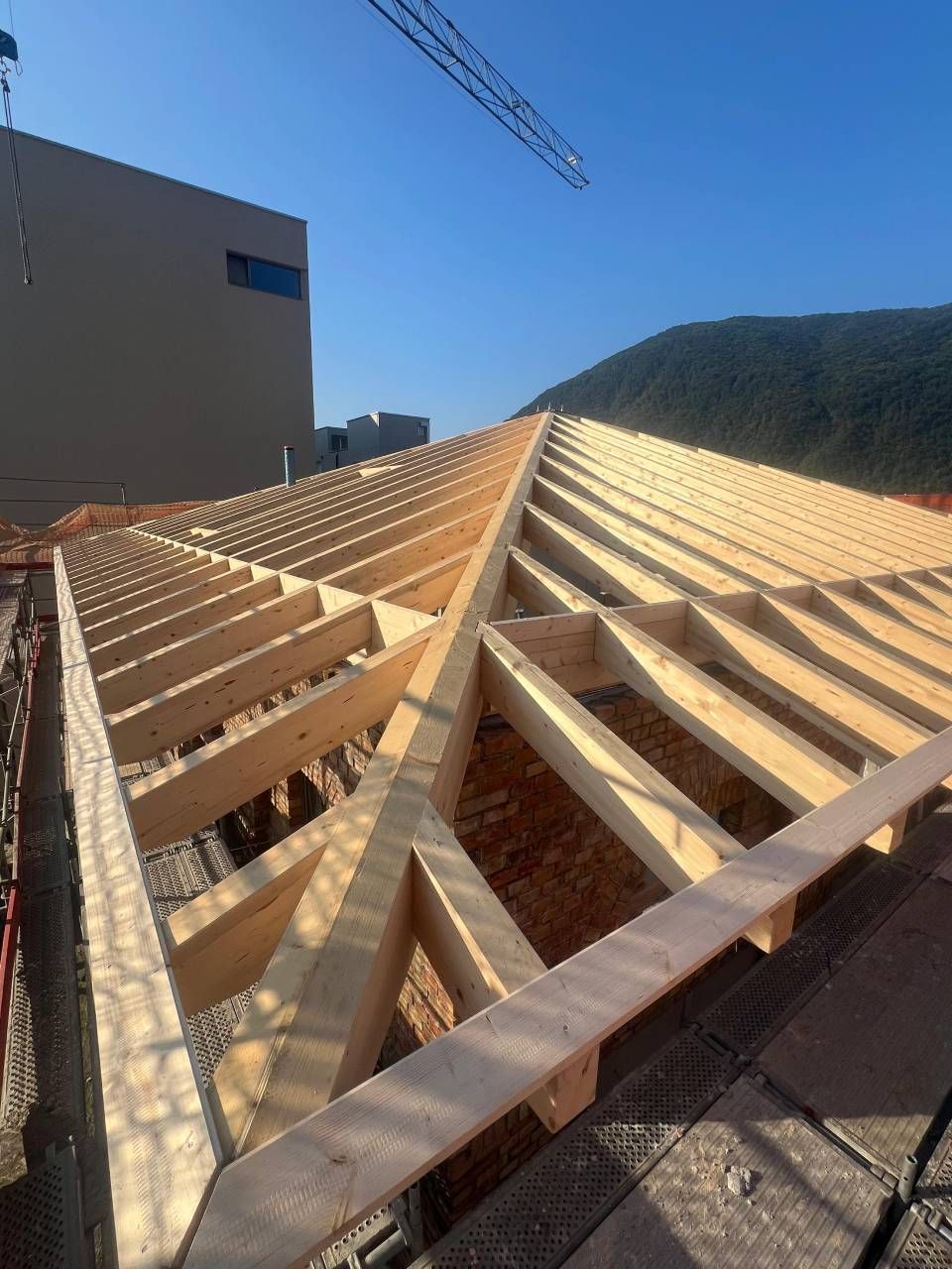 Struttura del tetto in legno in costruzione con sfondo di cielo azzurro.