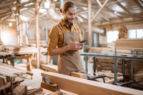 Un menuisier dans son atelier en train de consulter son téléphone