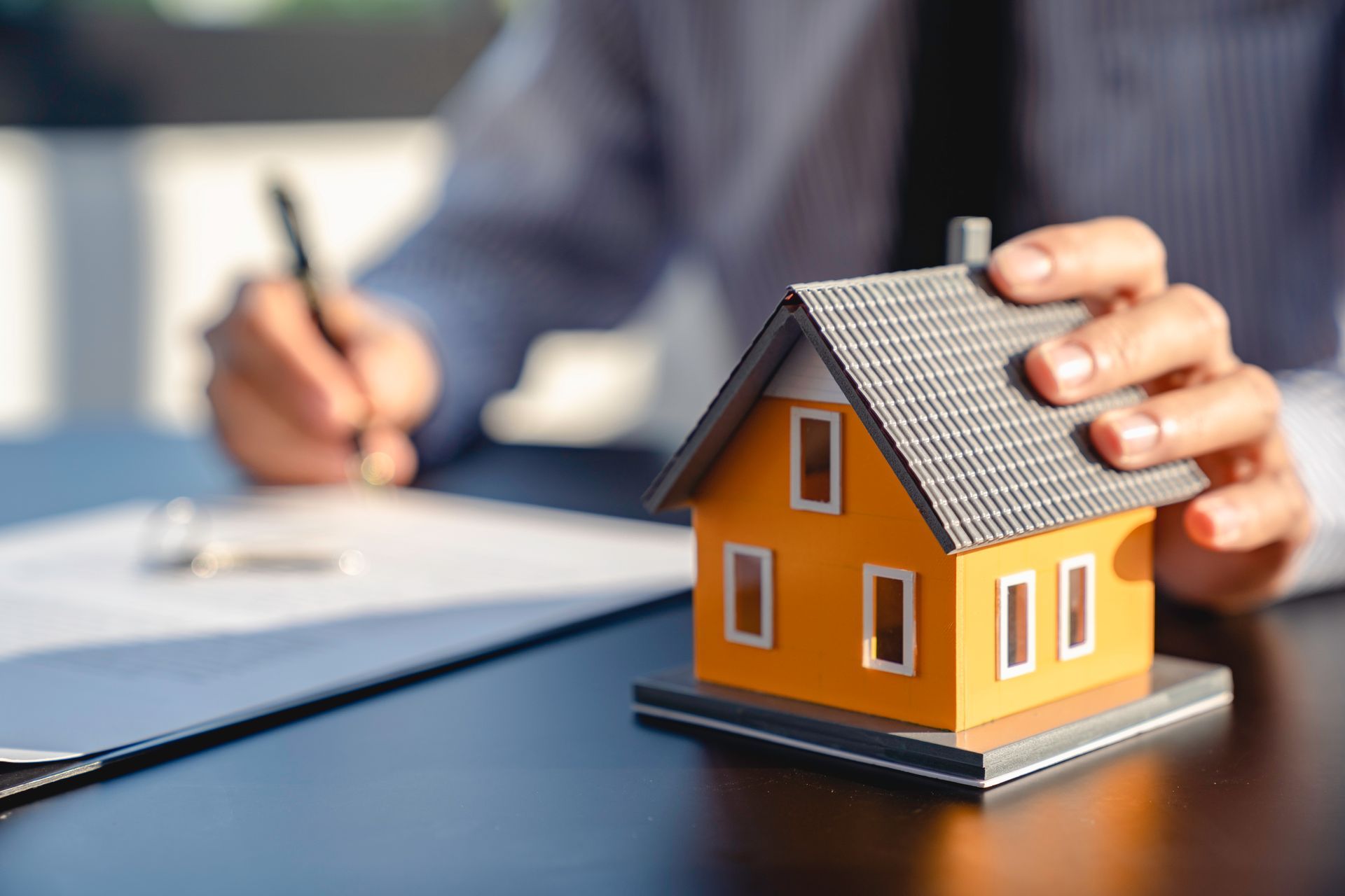 Un assureur avec sa main sur une maquette de maison
