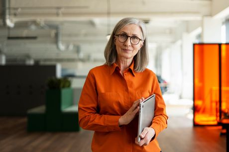 Une femme élégante d'une soixantaines d'année avec un ordinateur à la main