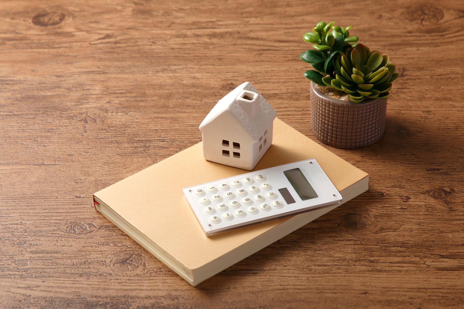 Un bloc note jaune avec une calculatrice et une maquette de maison