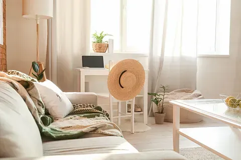 Una sala de estar con un sofá, una mesa, una silla y un sombrero de paja.