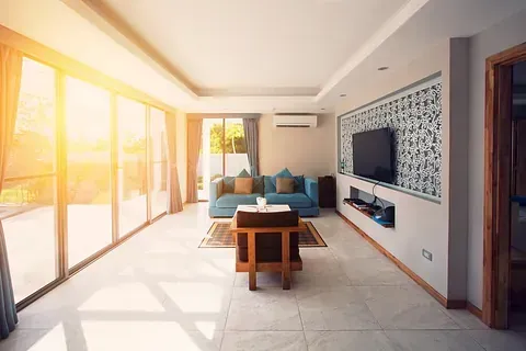 Una sala de estar con sofá, silla, mesa y televisión.