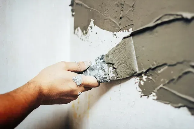 Una persona está enyesando una pared con una espátula.