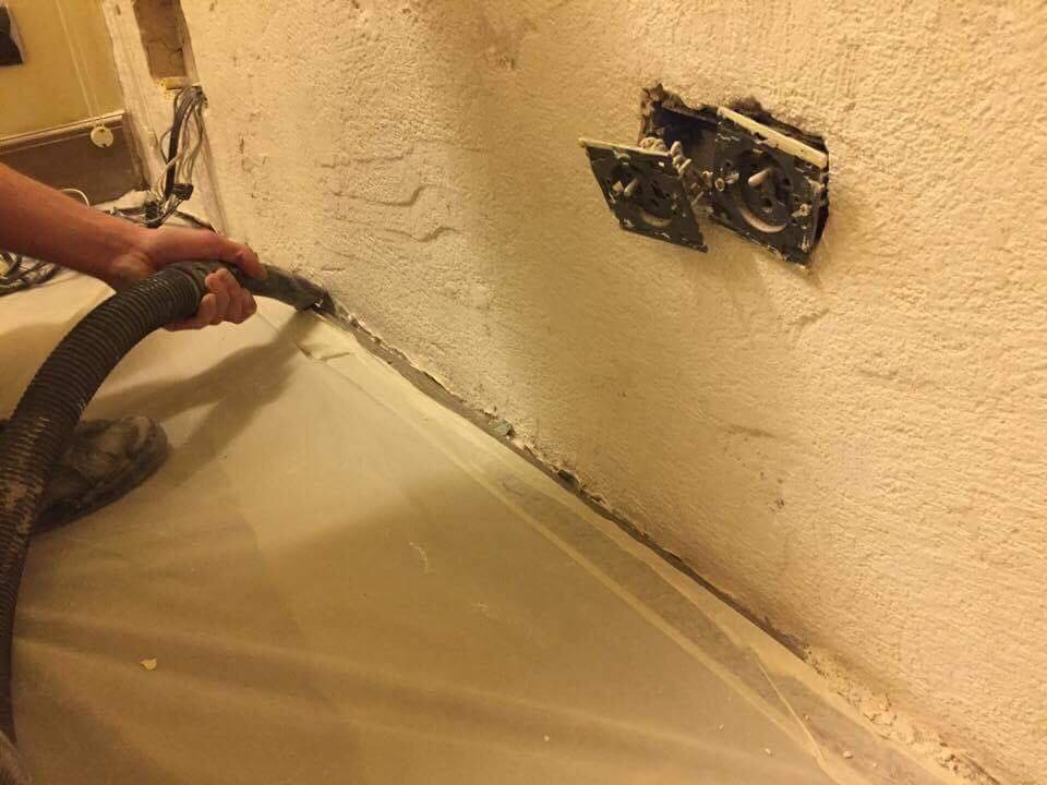 Professionnel appliquant une nouvelle résine en bas d'un mur en prévision d'un cuvelage