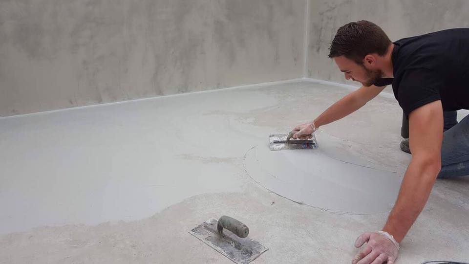 Professionnel appliquant une résine dans le fond d'une piscine à l'aide d'une truelle