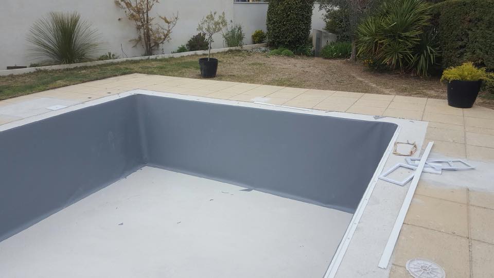 Piscine en construction avec une couche de résine grise posée sur ses parois