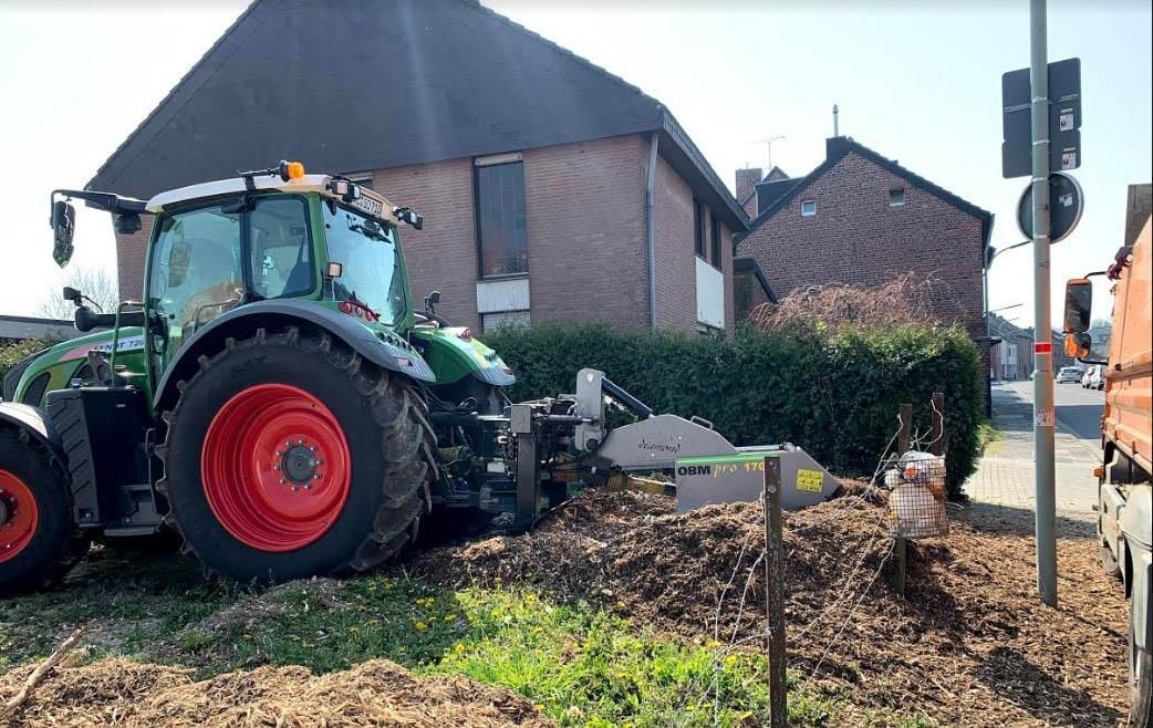 Ein grün-roter Traktor steht vor einem Backsteinhaus
