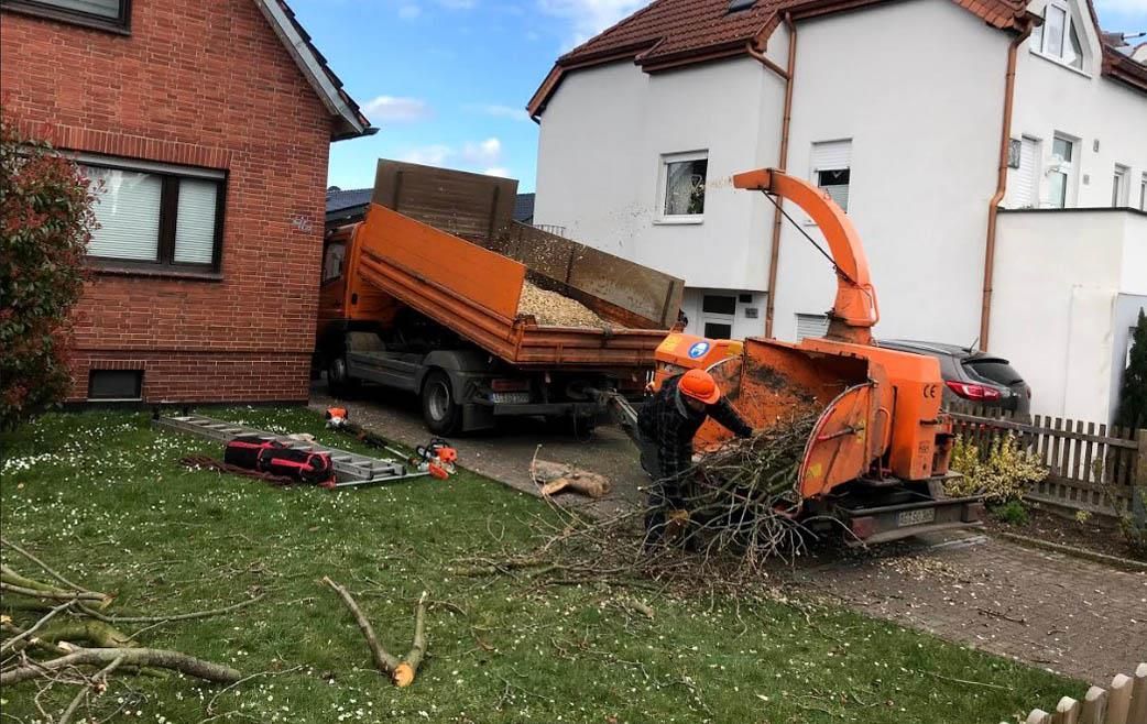 Ein orangefarbener Lastwagen steht vor einem Haus