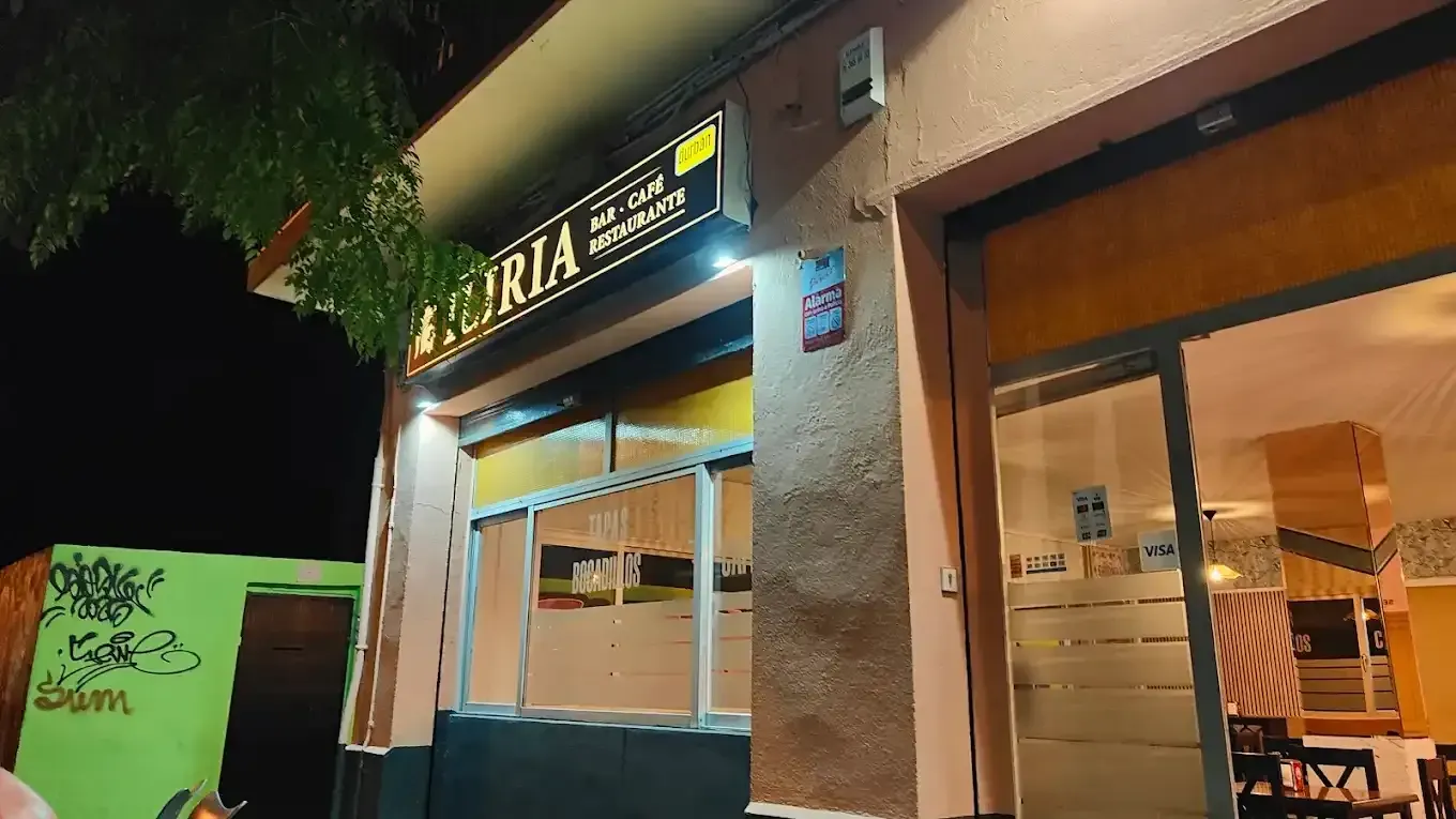 Una pizzería de noche con cartel amarillo y exterior naranja y rosa.