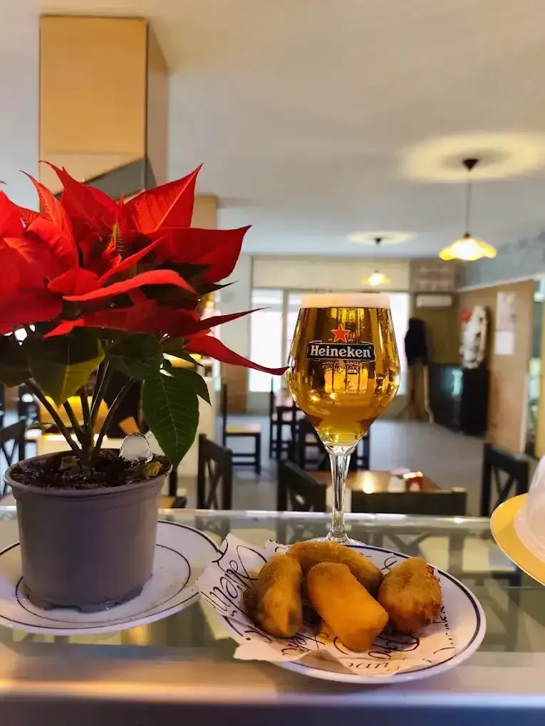 Un vaso de cerveza y comida frita en un plato en un bar, con una flor de Pascua en primer plano.