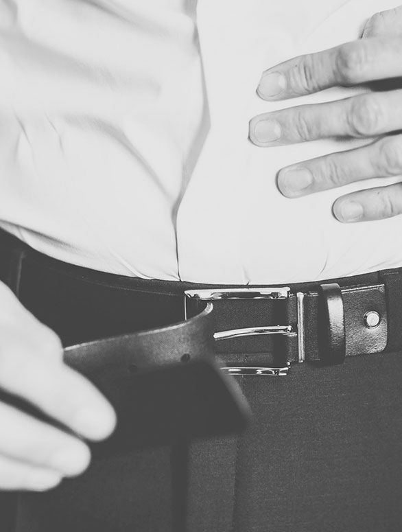 Un hombre con camisa blanca se ajusta el cinturón.