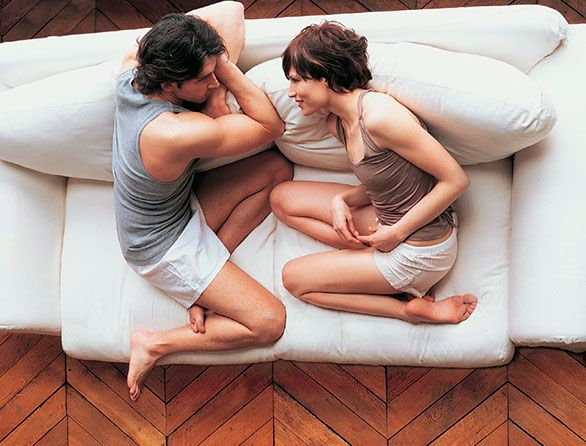 Un hombre y una mujer están acostados en un sofá mirándose.