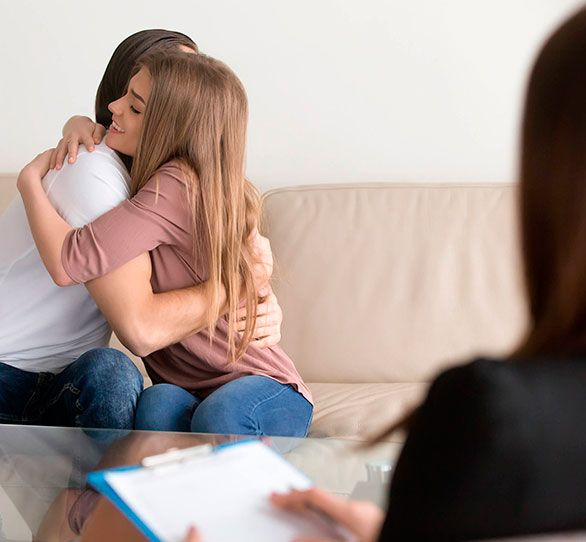 Un hombre y una mujer se abrazan mientras están sentados en un sofá.