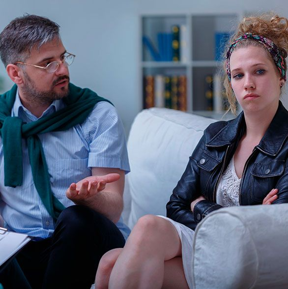 Un hombre y una mujer están sentados en un sofá conversando.