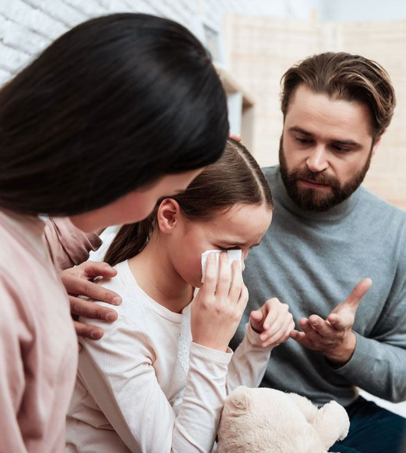 Una niña llora mientras sus padres la consuelan.