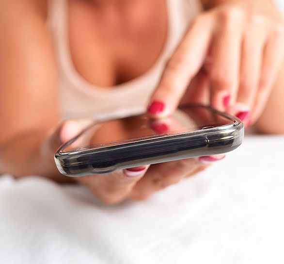 Una mujer con uñas rojas está usando un teléfono celular.