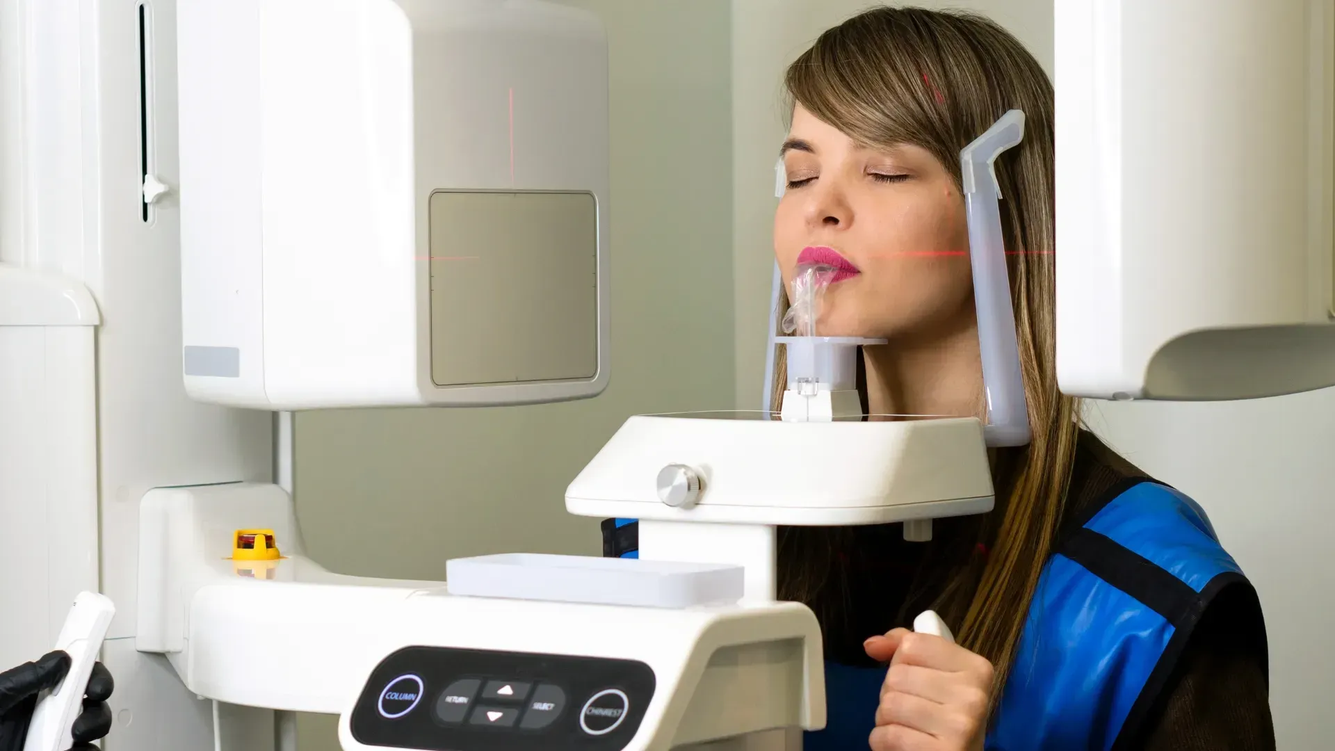 Dientes con alineador transparente en la boca, vista lateral, sobre un fondo azul.