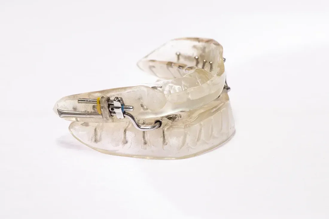 Aparato bucal de plástico transparente, probablemente para apnea del sueño o bruxismo, apoyado sobre una superficie blanca.