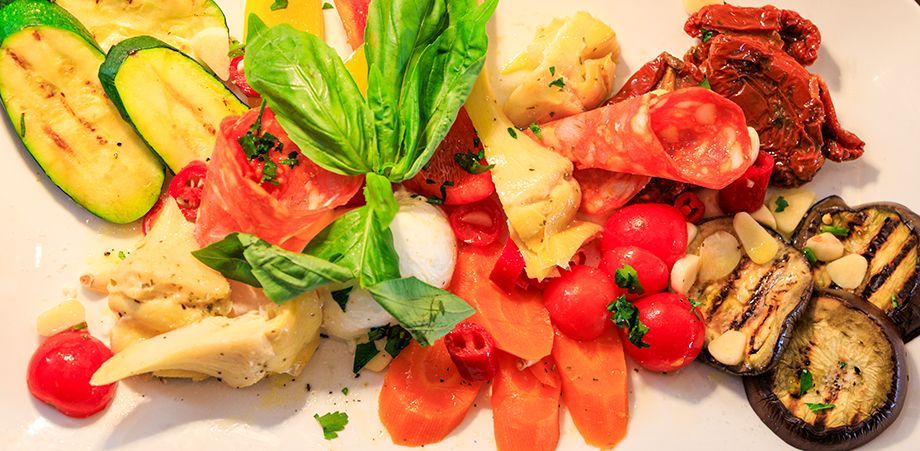 Eine farbenfrohe Antipasti-Platte mit gegrilltem Gemüse, Tomaten und Wurstwaren. noiduo glindow