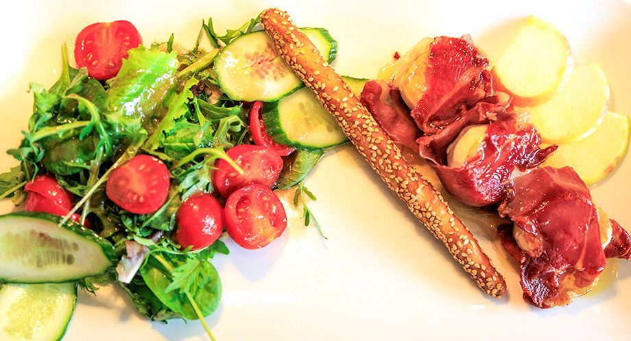 Salat mit Tomaten und Gurken, Grissini, Kartoffelscheiben und Prosciutto auf einem weißen Teller. noiduo glindow