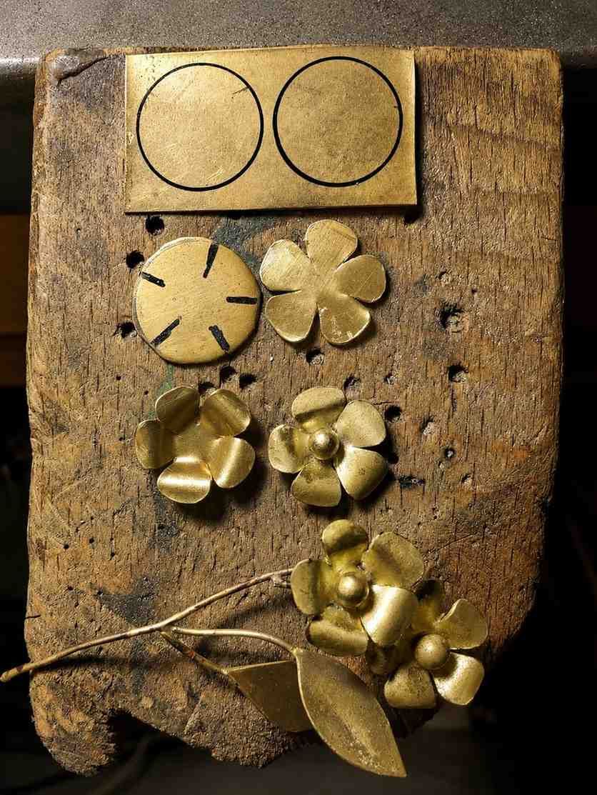 Flores de metal hechas a mano que se sueldan con un soplete sobre una superficie de trabajo.