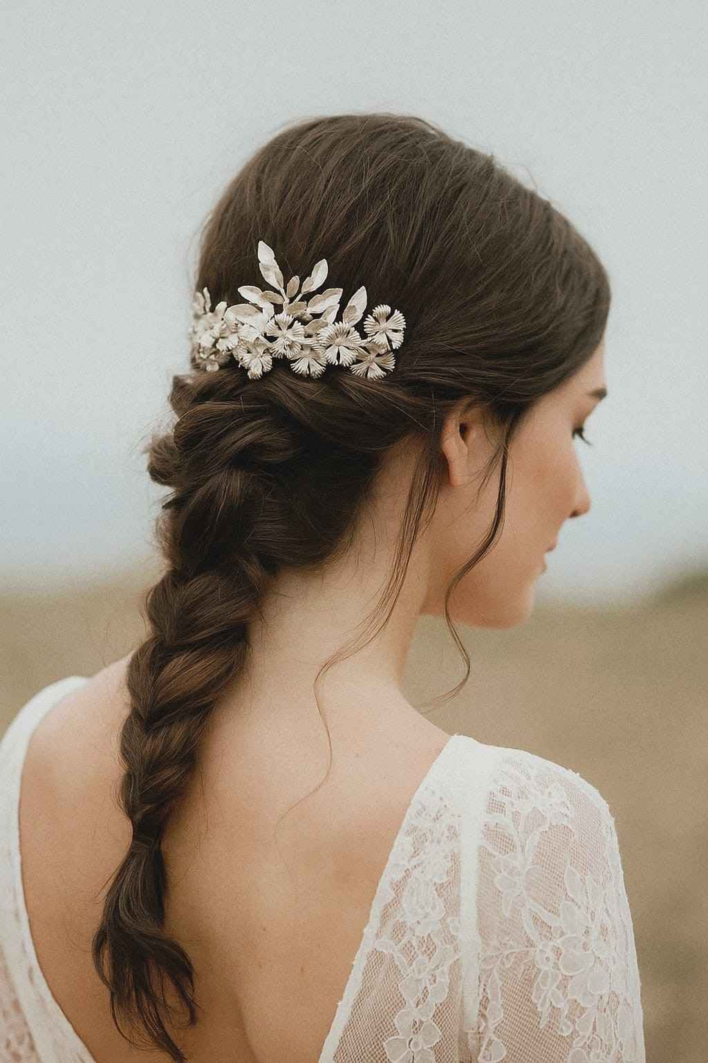 Moño recogido con trenzas y adorno floral en una mujer con un vestido blanco de encaje, visto desde atrás.