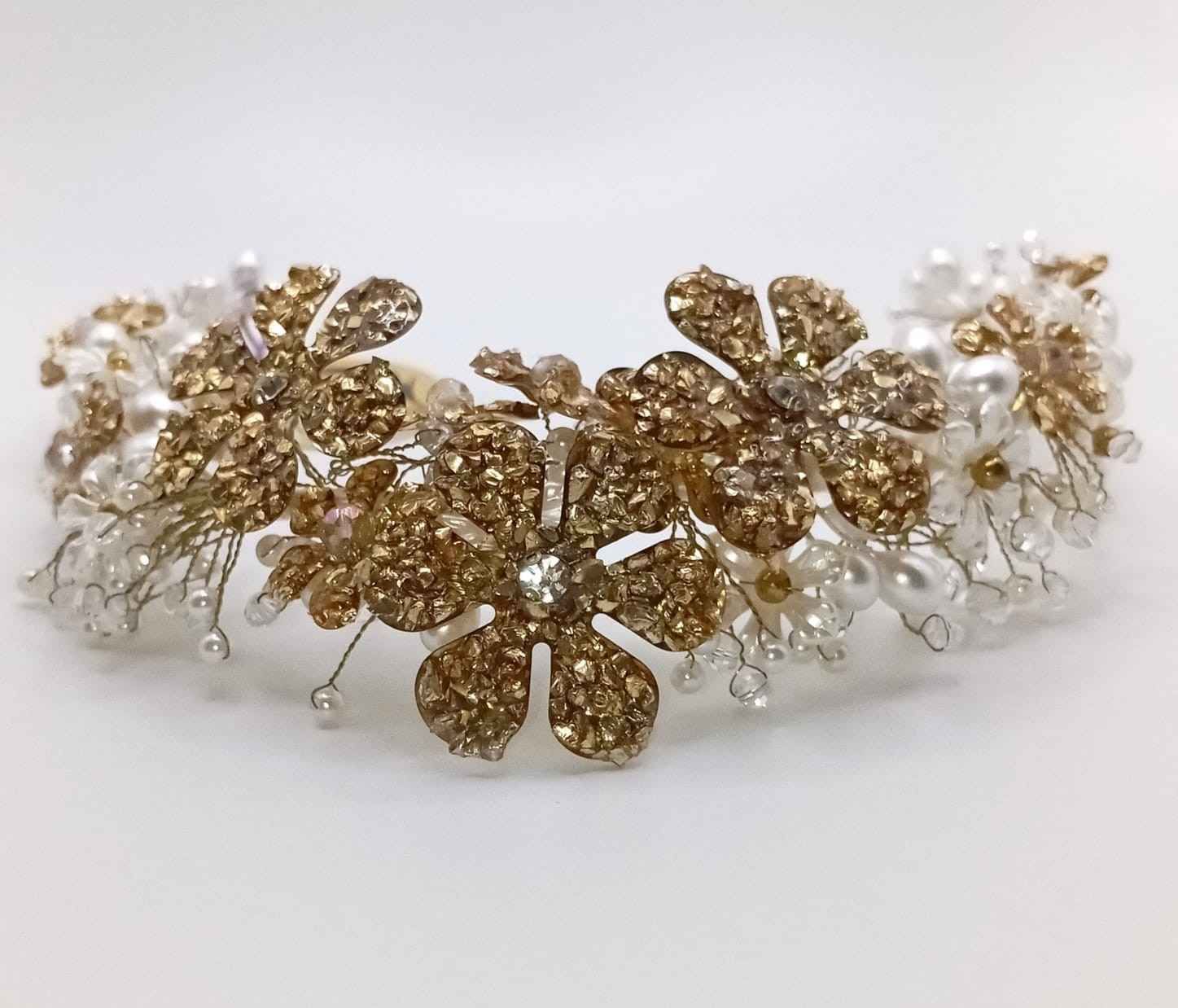 Tiara floral de oro y cristal transparente con detalles que imitan perlas sobre un fondo blanco.