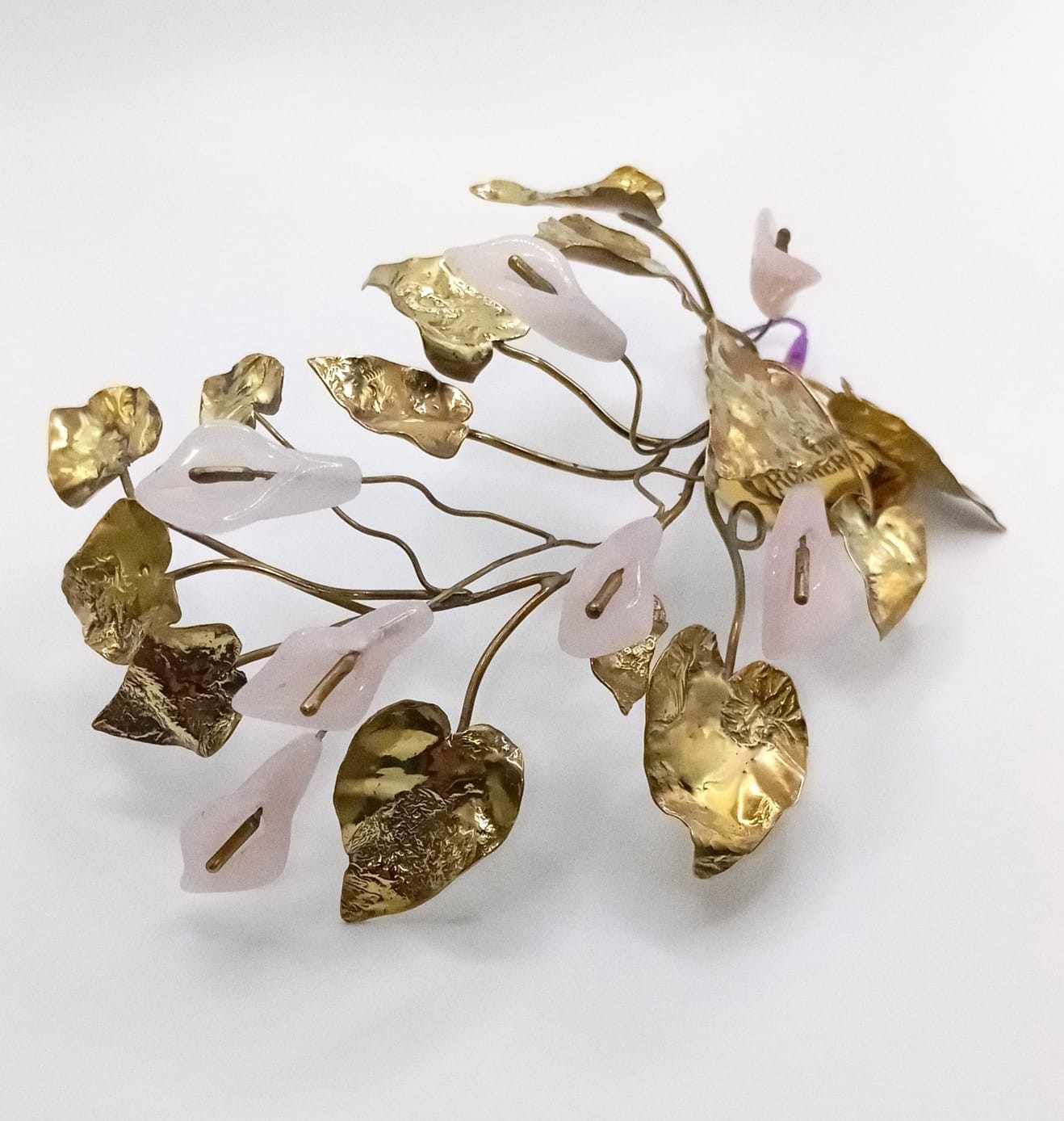 Delicado accesorio para el cabello en forma de hoja, de color dorado y rosa pálido, sobre un fondo blanco.