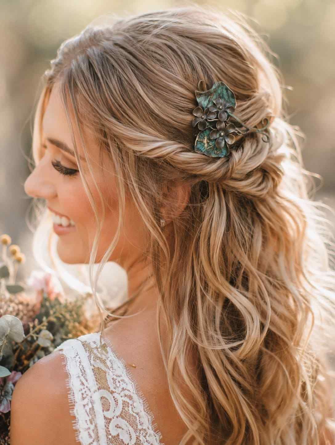 Peinado de novia con tocado floral enjoyado y ondas sueltas, fotografiado bajo la suave luz del sol.