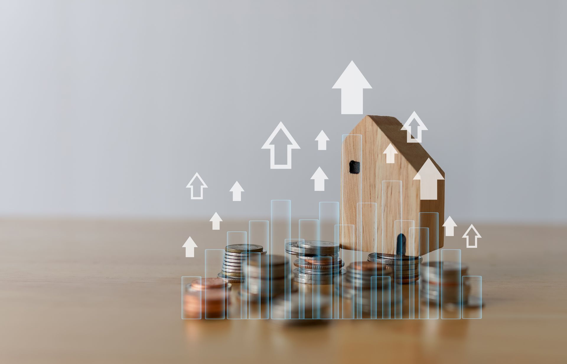 Maquette de maison en bois posée sur des piles de pièces de monnaie avec des flèches pointant vers le haut, représentant la croissance des investissements immobiliers.